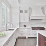 White kitchen with central island, hardwood flooring, and pendant lighting in an Apex NC home renovation