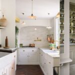 Luxury white kitchen featuring marble backsplash, gold hardware, and custom cabinetry in a Durham North Carolina home